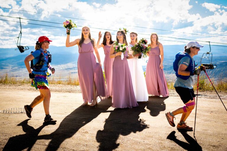 A bride and her bridesmaids cheer on runners who passed by during their bridal party portraits at the Four Points Lodge atop a mountain in Steamboat Springs, Colorado