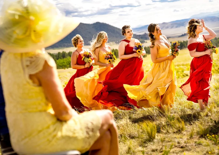 Bridesmaid dresses blow in the wind during a wedding ceremony at Thisreed Lodge Florissant, Colorado.