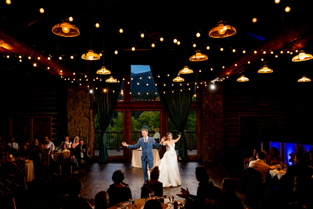 A bride and groom gesture to their wedding guests after their first dance