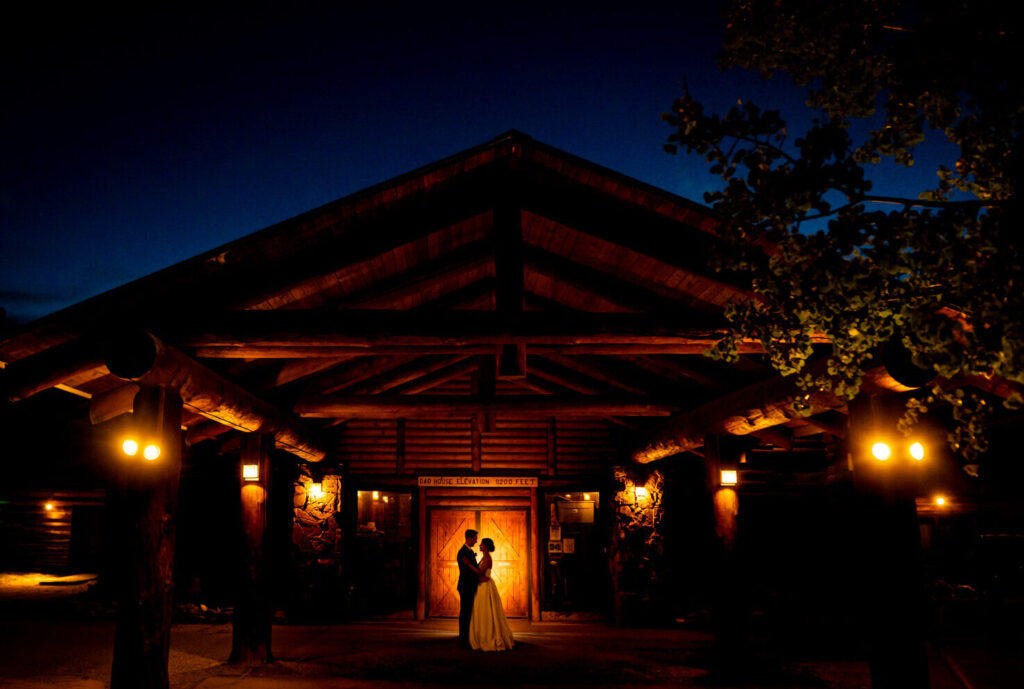 A bride and groom are silhouetted in front of the doors to the Dao House during their wedding