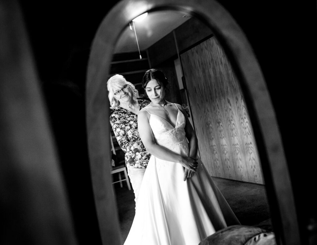 A bride gets into her wedding gown in front of a mirror in Dao House