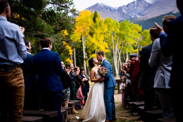 A documentary style wedding photo of a bride and groom kissing during their wedding ceremony at Dao House in Estes Park