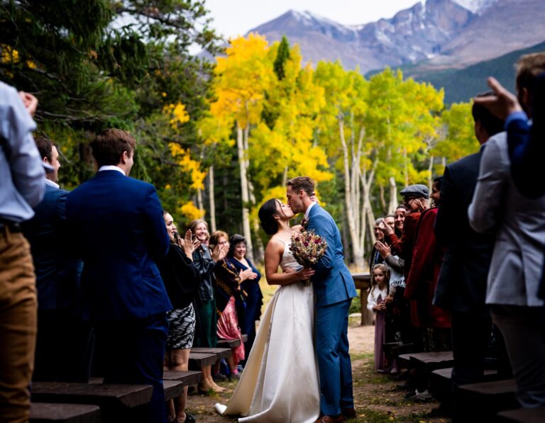 A documentary style wedding photo of a bride and groom kissing during their wedding ceremony at Dao House in Estes Park