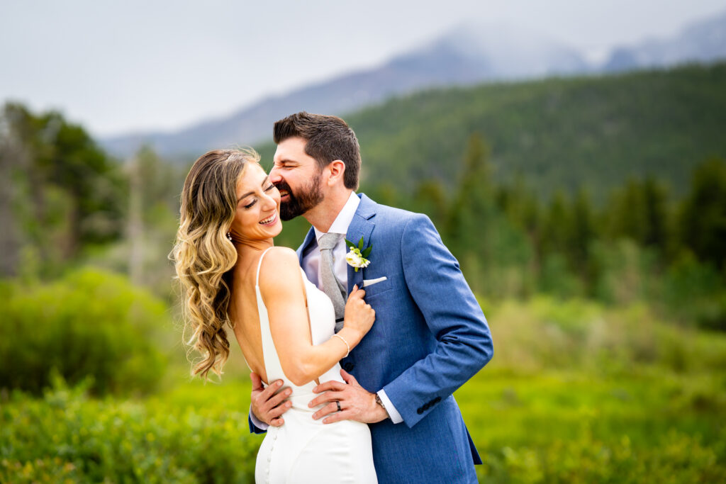 A bride and groom laugh during a documentary style wedding portrait session at Lily Lake in Estes Park, Colorado