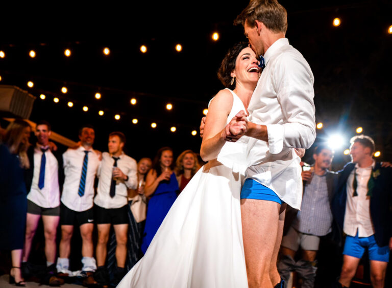 A bride laughs as her groom dances with her with his pants around his ankles, captured in a candid documentary wedding photography style at Arum in Steamboat Springs, Colorado