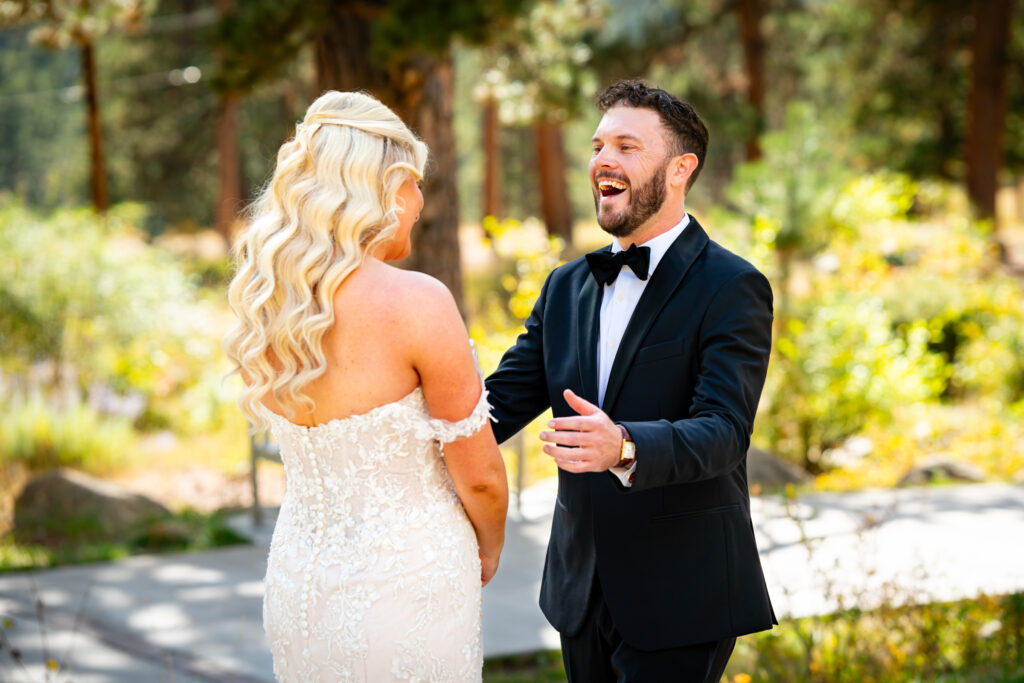 A joyful groom laughs after turning around to see his bride during first look of their Della Terra Mountain Chateau wedding