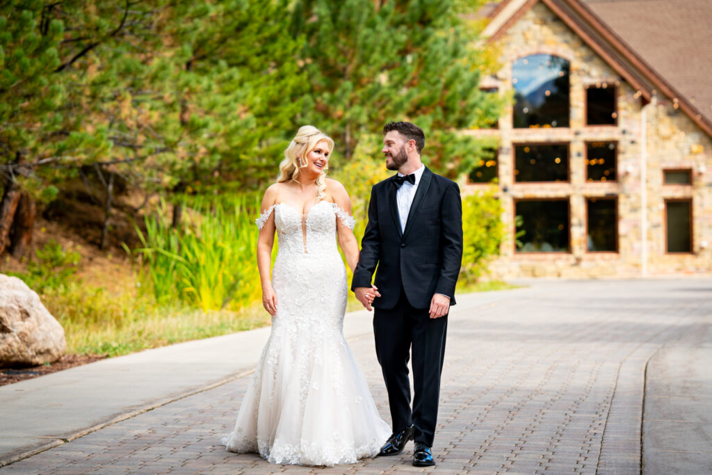 A bride and groom holds hands walking in front of Della Terra Mountain Chateau during their wedding