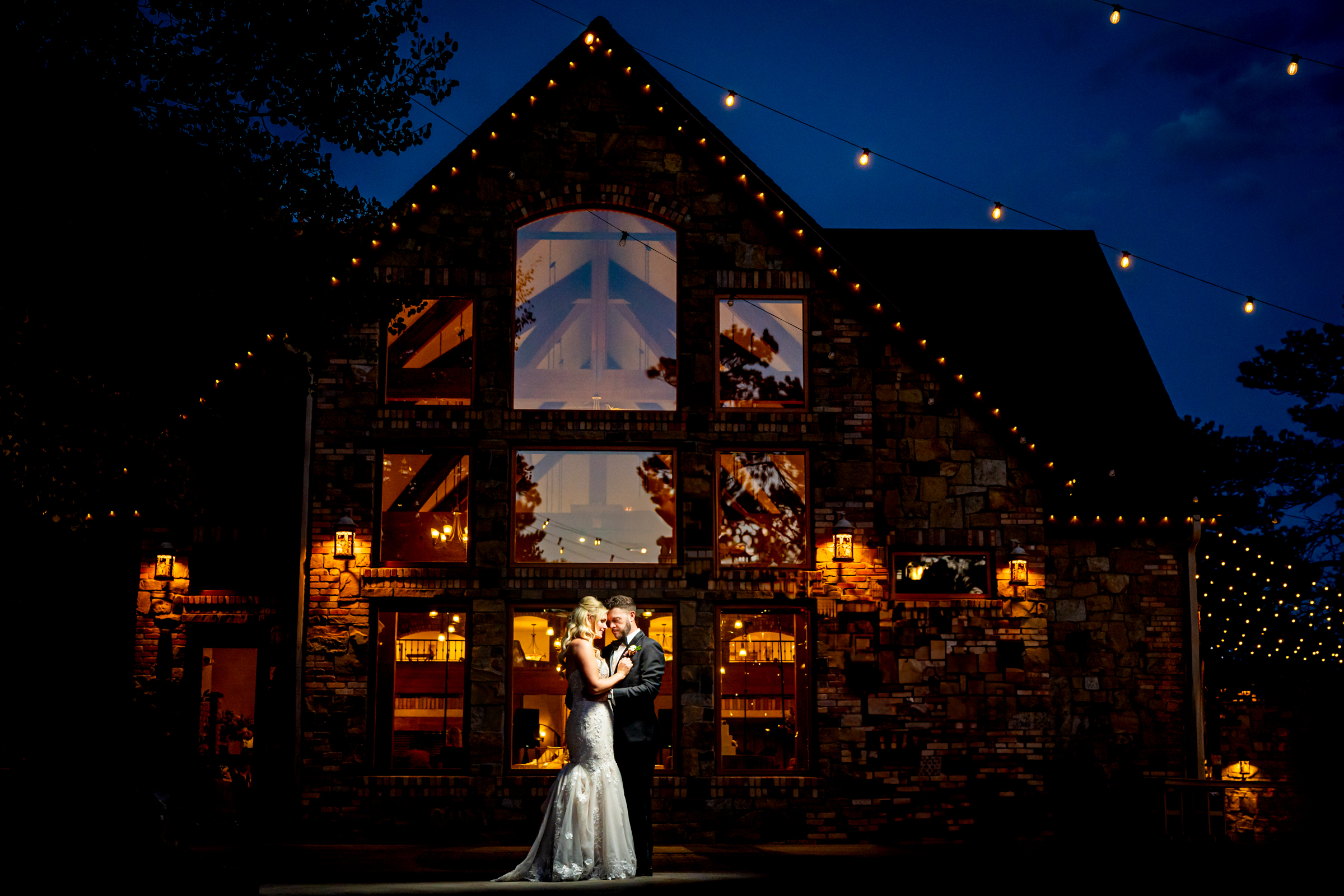 At night, Della Terra Mountain Chateau casts a soft glow on the newlywed as they take portraits under the night sky.