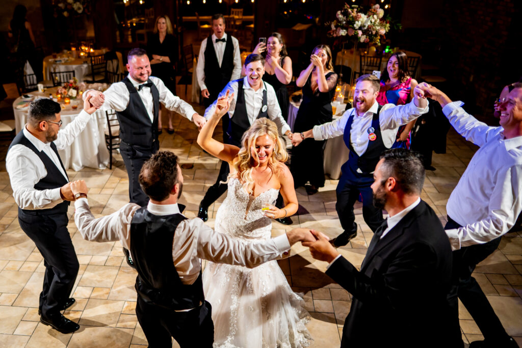 Surrounded by dancing groomsmen and her new husband, a bride dances during the reception of her Della Terra Mountain Chateau wedding