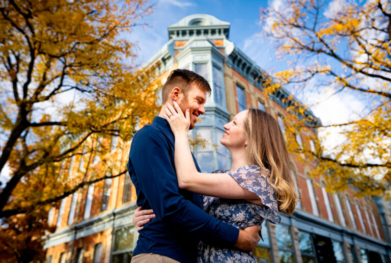 A couple embraces in front of historic building in Fort Collins, Colorado