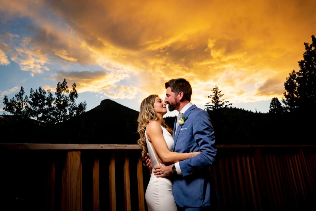 Sunset photos of a bride and groom on the balcony at Dao House Retreat with the mountains behind them in Estes Park