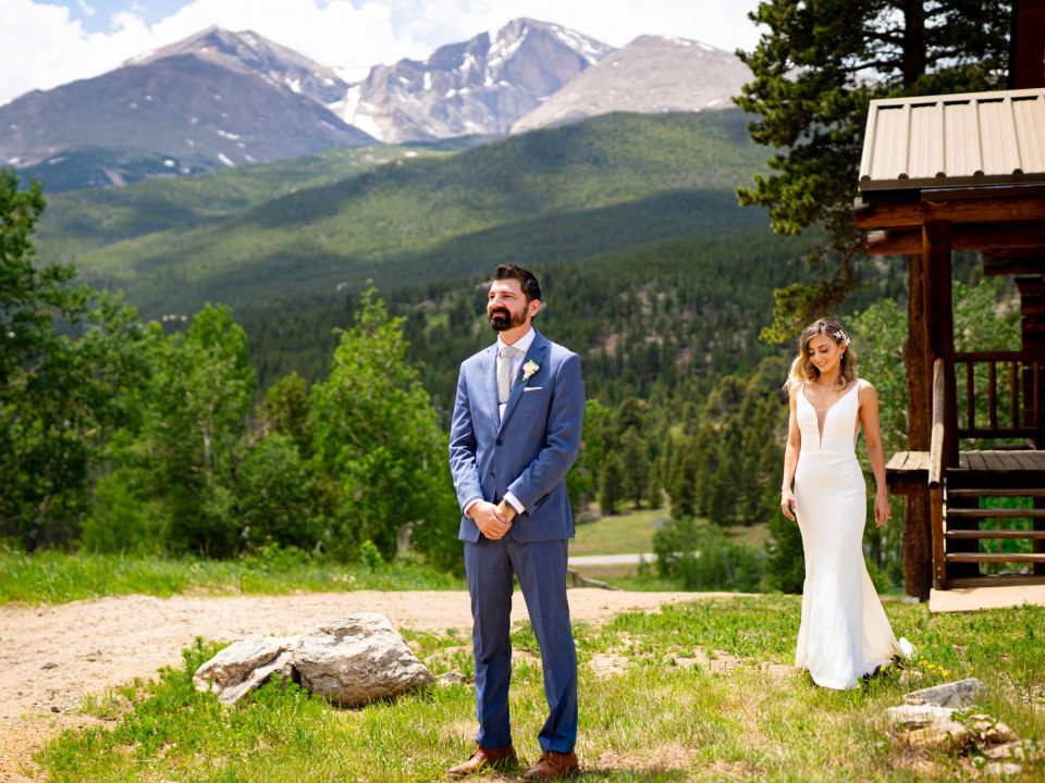 A groom stands with his back to his bride and the mountains in the background right before their first look at Dao House