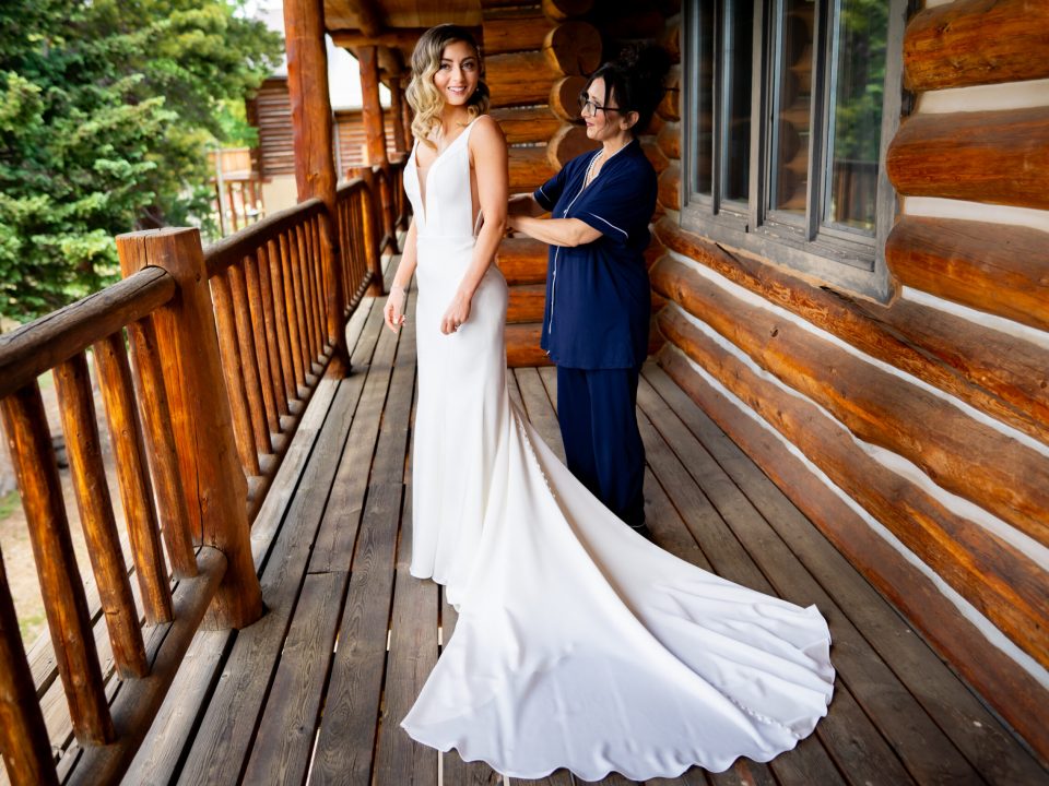 A bride stands on a balcony at the Dao House as her mother helps her get into her gown